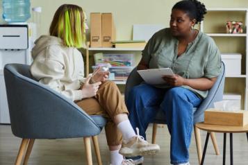 2 women sitting in chairs and talking